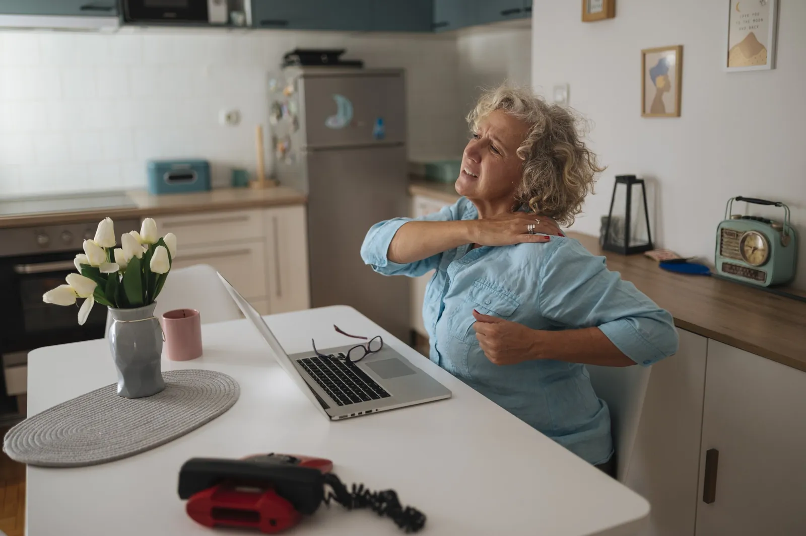 在宅オフィスでノートPCを前にストレッチする女性