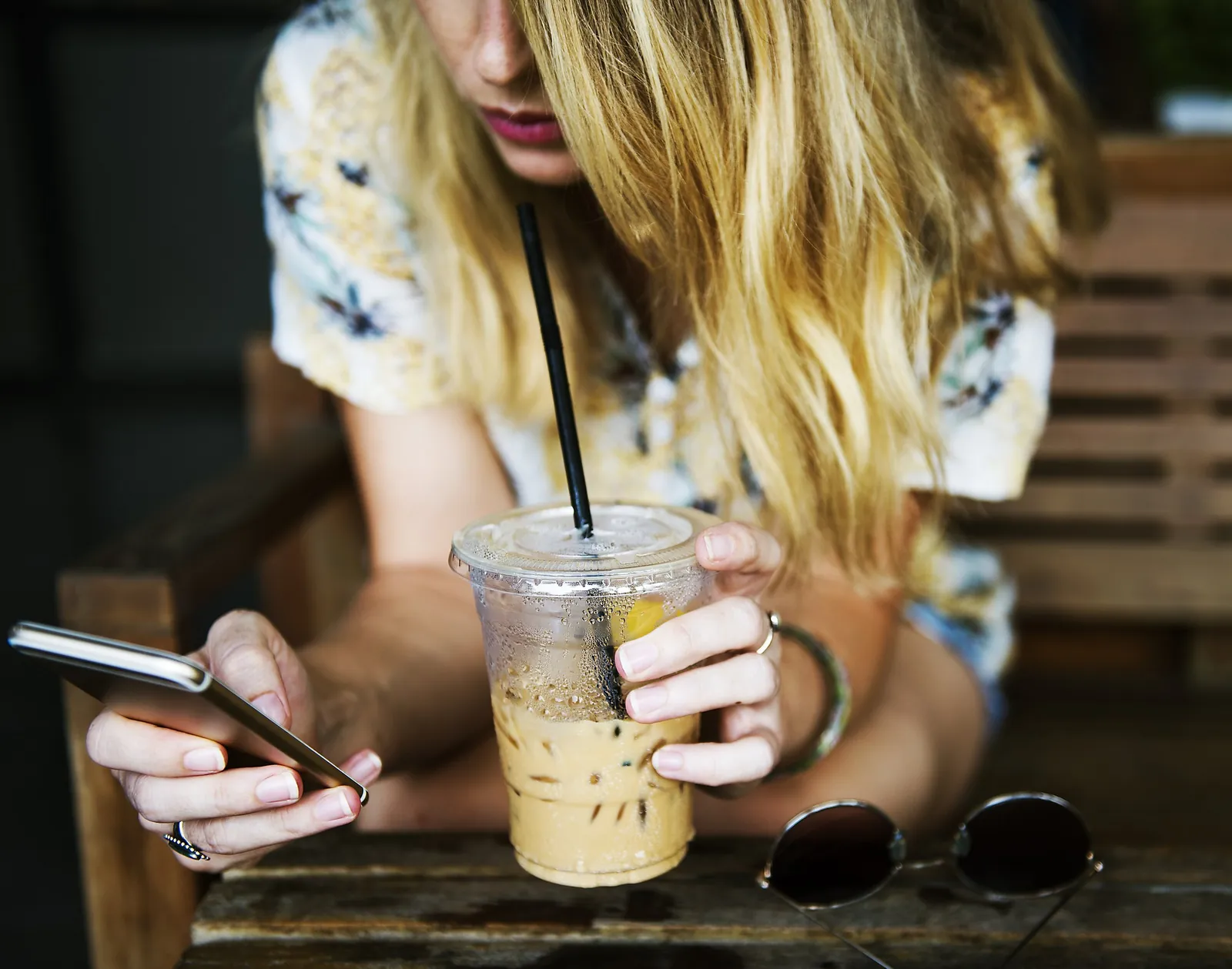 アイスコーヒーを片手にスマートフォンを操作する女性